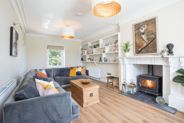 Bright living room with a large sofa and wood-burning stove at Bron Menai